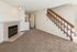 Charming living area with cozy fireplace and elegant staircase, boasting a bright and inviting atmosphere.