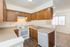 Charming kitchen with warm wooden cabinetry, modern appliances, and airy layout leading to a bright living area.