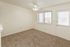 Bright and cozy carpeted room with large windows and a ceiling fan, perfect for relaxation and comfort.