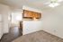 Charming open-concept apartment featuring a cozy kitchen with wooden cabinets, plush carpeted flooring, and bright natural light.