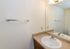 Bright and elegant bathroom with a large mirror, sleek countertop, and modern fixtures, offering a clean and inviting space.