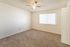 Bright and spacious bedroom with cozy carpet flooring, large window, and ceiling fan, perfect for relaxation.