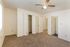 Bright, spacious bedroom with new carpeting, ceiling fan, and open closet doors, showcasing modern comfort.