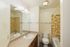 Bright bathroom with elegant beige tiles, modern sink, spacious mirror, and classic bathtub.