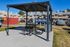 Charming outdoor picnic area under a modern gazebo, surrounded by picturesque townhouses and lush greenery, perfect for community gatherings.