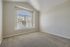 Bright and airy room with vaulted ceiling, large arched window, and plush carpeting, offering abundant natural light.