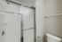 Modern bathroom featuring a sleek glass shower with chrome fixtures, next to a pristine white toilet.