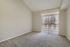 Bright and inviting empty room with plush carpeting and large sliding glass doors leading to a balcony, perfect for creating a personalized living space.