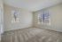 Bright and inviting room with large windows, plush carpeting, and neutral walls perfect for personalization.