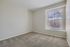 Inviting empty room with plush carpet and sunlit window, perfect for personalized design and cozy living.