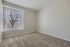 Bright room with plush carpet and large window offering serene tree views, perfect for a cozy retreat.