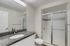 Modern bathroom with elegant granite countertop, sleek faucet, and spacious shower with glass door.