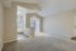 Bright and spacious open-plan living room with plush carpet, featuring a connected kitchen with sleek countertops and natural light from large windows.