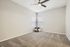 Bright and airy room featuring plush carpeting, modern ceiling fan, and cozy corner with pillows.