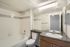 Modern and clean bathroom featuring sleek countertops, a full bathtub, and a large mirror offering a touch of elegance.