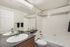 Modern bathroom featuring sleek granite countertop, spacious mirror, and pristine white tile bathtub.