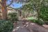 Charming apartment complex nestled in lush greenery, featuring a serene pathway and expansive lawn for relaxation.