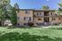 Inviting brick apartment building surrounded by lush greenery, showcasing charming balconies and a welcoming entrance.