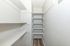 Bright, spacious closet featuring sleek built-in shelving and elegant wood flooring, perfect for organized storage.