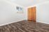 Bright and airy room showcasing elegant wood flooring, modern blinds, and a cozy closet with wooden doors.
