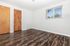 Inviting room with wood laminate flooring, polished wooden doors, and a bright window view creating a cozy ambiance.