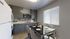 Modern kitchen with sleek gray cabinets, stylish backsplash, and a cozy dining area set by a bright window.