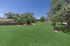 Expansive green outdoor space with a charming wooden arbor and a classic grill, perfect for relaxation and social gatherings.