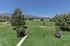 Beautiful green park with walking paths, surrounded by lush trees and stunning mountain views.