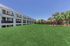 Expansive grassy courtyard with a modern apartment building and charming gazebo, perfect for outdoor relaxation.