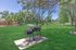 Inviting outdoor space with a charming grill on lush green lawn, framed by trees and scenic mountain views.