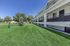 Charming apartment exterior with well-maintained lawns and spacious balconies, set against a lush green landscape.