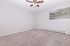 Bright and airy room with plush carpeting, large window, and elegant ceiling fan, perfect for a cozy retreat.