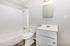 Modern bathroom with sleek fixtures, featuring a bathtub, toilet, and vanity with a mirror, accented by stylish flooring.