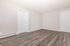 Bright, freshly renovated room with elegant wood flooring and dual white-paneled doors, perfect for creating a cozy living space.