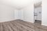 Bright and inviting apartment featuring sleek wood flooring, neutral wall tones, and a glimpse of a modern kitchen.