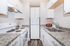 Bright, compact kitchen with modern white cabinets, marble-patterned countertops, and sleek appliances.
