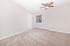 Bright and modern bedroom with plush carpet, ceiling fan, and natural light pouring through the window.