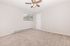 Bright and spacious bedroom with plush carpeting, ceiling fan, and large window offering serene outdoor views.