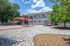 Charming apartment exterior with lush green trees and a stylish pergola over a picnic area, creating a perfect outdoor retreat.
