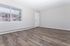 Bright, airy apartment interior with large window, modern laminate flooring, and freshly painted walls.