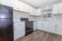 Bright modern kitchen with sleek black appliances, elegant white cabinetry, and stylish wood flooring.