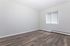 Bright empty room with stylish hardwood floors and a large window letting in natural light, perfect for versatile living arrangements.