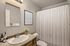 Elegant bathroom featuring a clean vanity, modern mirror, and refreshing shower with a soft white curtain.