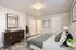 Chic modern bedroom with elegant decor, featuring a cozy bed with plush pillows, stylish wooden dresser, and bright natural accents.