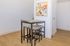 Modern dining area featuring a sleek table with four minimalist stools, vibrant abstract artwork, and elegant wooden flooring.