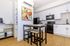 Modern kitchen with sleek white cabinets, vibrant abstract art, and a chic breakfast bar, accented by stylish black appliances and warm wooden floors.