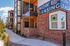 Modern apartment building with red brick exterior and floor-to-ceiling windows, prominently displaying 'Now Leasing' sign with a welcoming leasing office entrance.