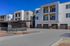 Contemporary apartment complex with stylish balconies, spacious garages, and sleek design under a bright blue sky.