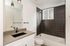 Modern bathroom with sleek black tiled shower, elegant white vanity, and contemporary fixtures creating a stylish and inviting atmosphere.