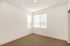 Bright and inviting corner room with large windows and plush carpeting, ideal for a cozy bedroom or home office.